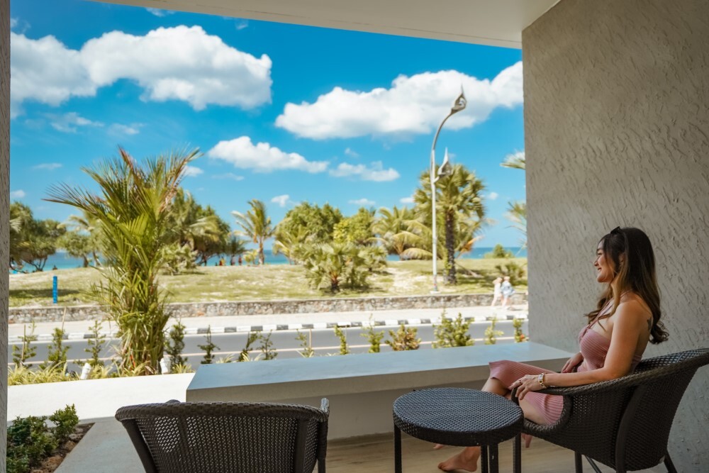 Guest relaxing on a private terrace with garden views at Thavorn Palm Beach, a MICE hotel in Phuket